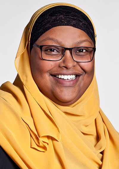 Portrait photo of woman weariing a yellow hijab smiling and looking into the camera. Photo.