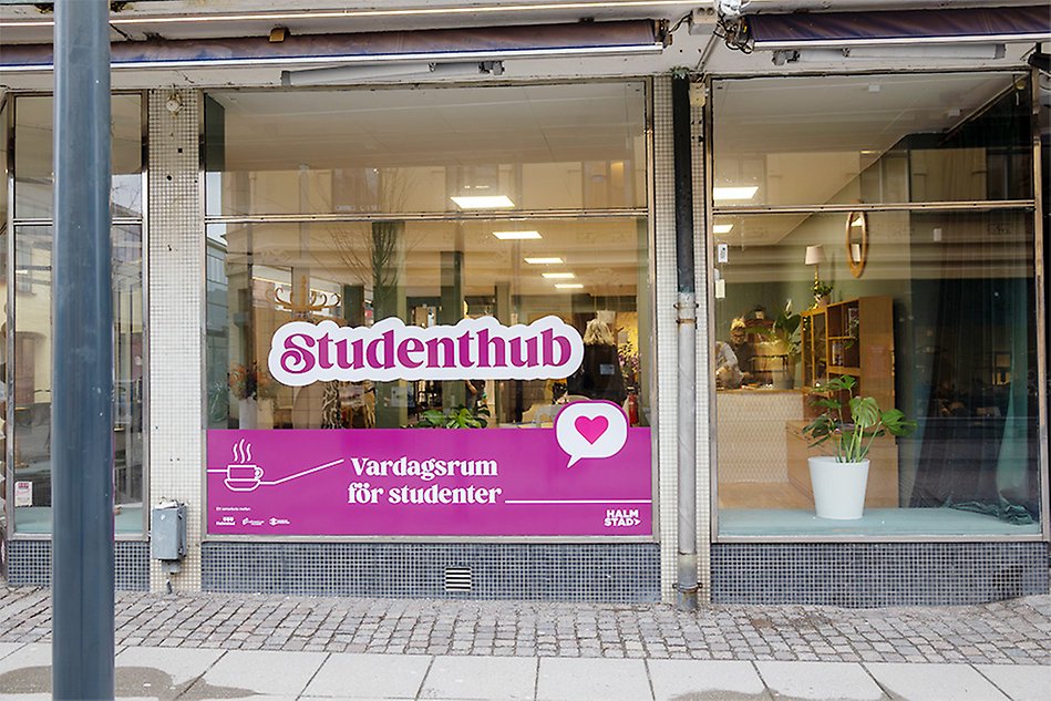 A house frontage with shop windows. The window pane has a plastic print with the text Studenthuben.