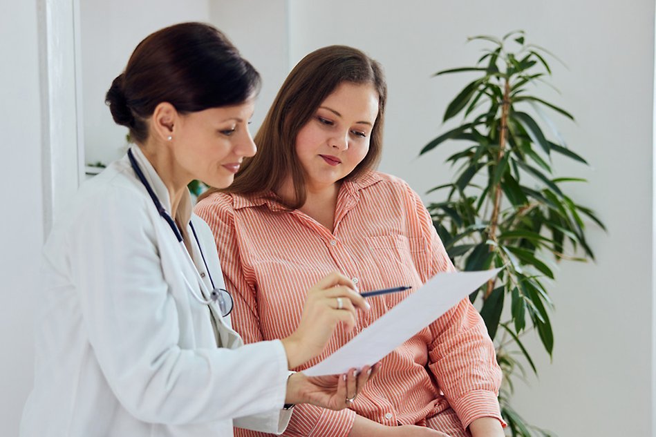 En läkare tittar på ett dokument tillsammans med en patient.