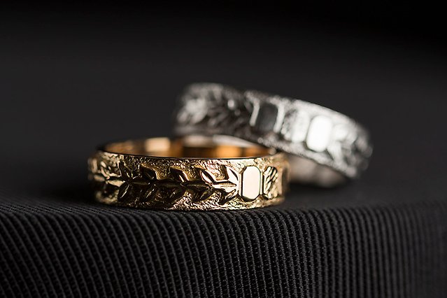 En ring i vitt guld ligger ovanpå en annan ring i rött guld mot svart bakgrund. Foto
