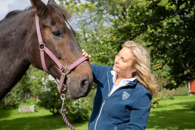 Person standing by a horse and looking at each other.