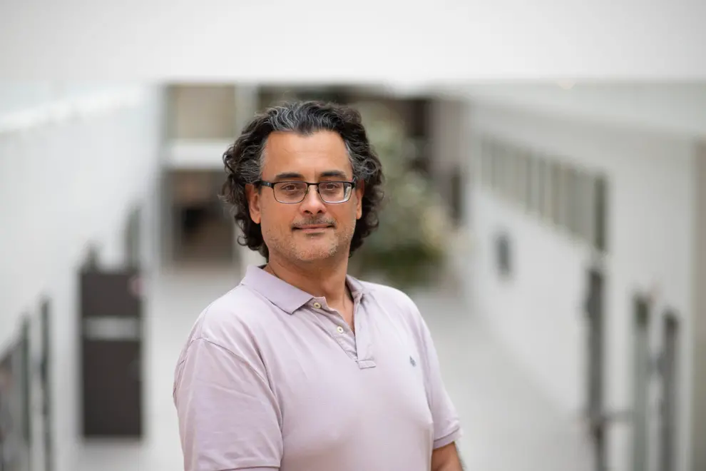 Man med glasögon och rosa poloskjorta. Foto.