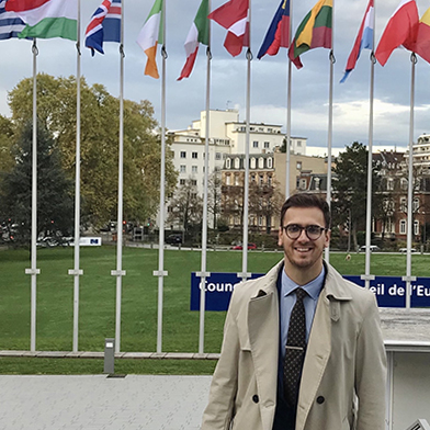 Man with brief case, flags in background.