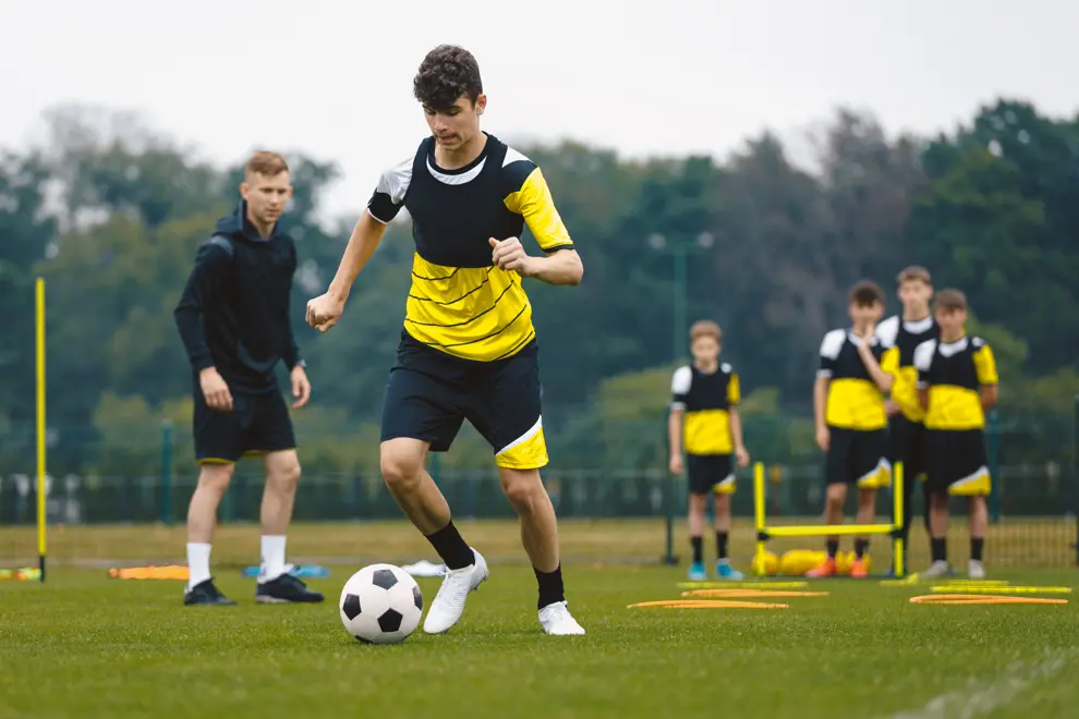 Person som dribblar en fotboll framför sig på en gräsplan