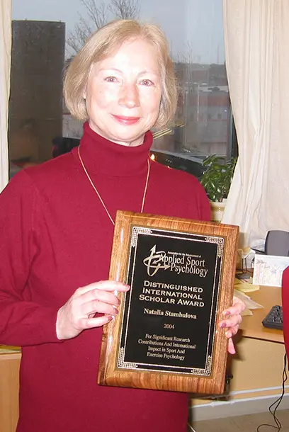 A person in a red sweater holds up a diploma. Photo.
