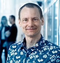 Man wearing button up with flowers pattern smiling into the camera.