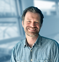 Man wearing light shirt looking into the camera smiling.