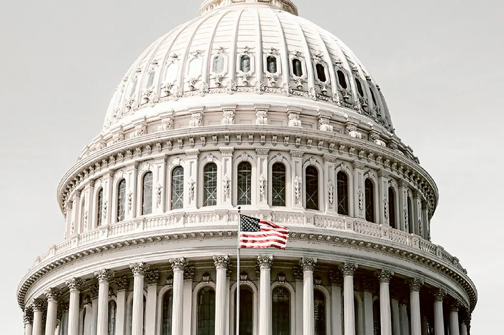 Kupolen på Kapitolium i Wahington DC med USA:s flagga i förgrunden. Foto  