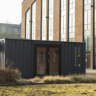 A container in front of a large building with many windows.