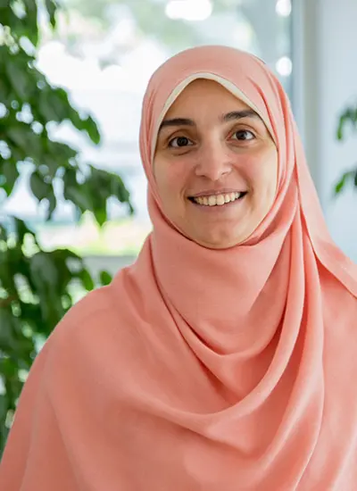 A woman in hijab smiling looking into the camera. Photo