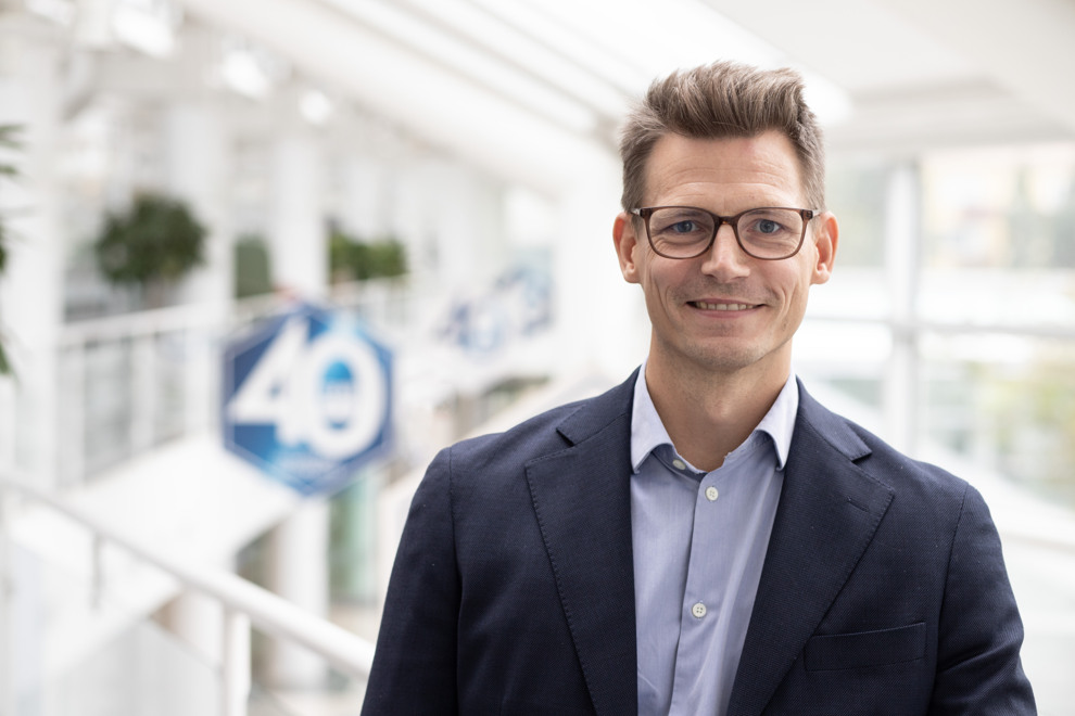 Porträtt av man som ler och tittar in i kameran. Foto