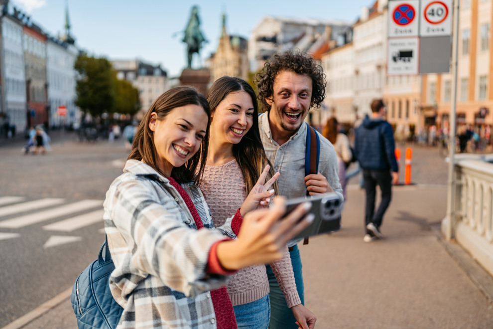 En grupp vänner som tar en selfie på en gata. Foto
