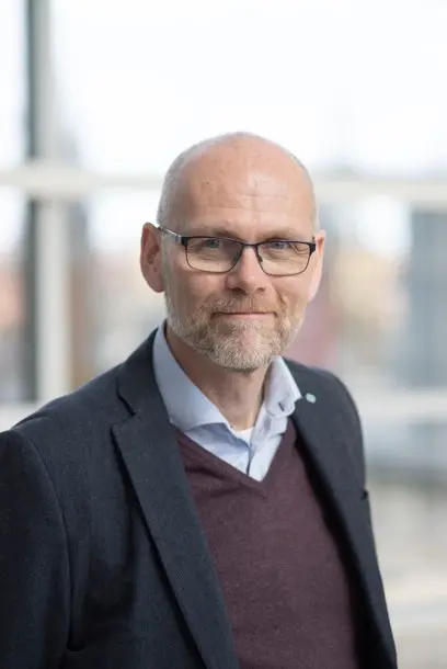 A man with glasses looking into the camera. Portrait photo.