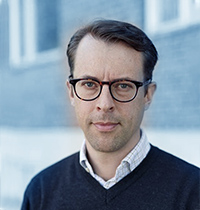 Man with glasses and brown hair looking into the camera.