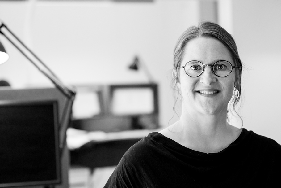 Black and white photo of a woman with glasses smiling at the camera.