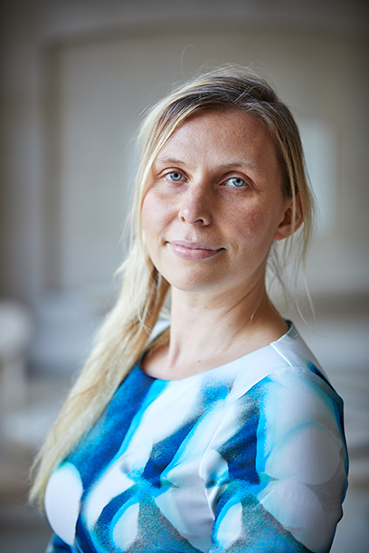 Woman with blonde hair and blue sweater looking into the camera. Photo.