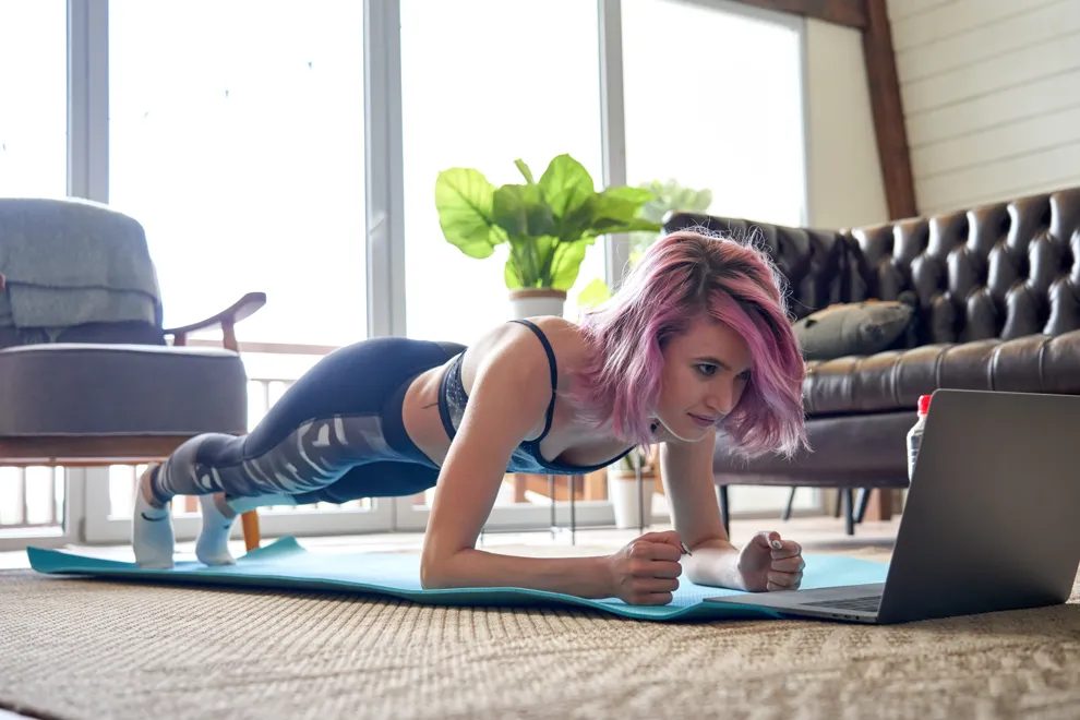 En kvinna står i så kallad planka på en yogamatta. Foto