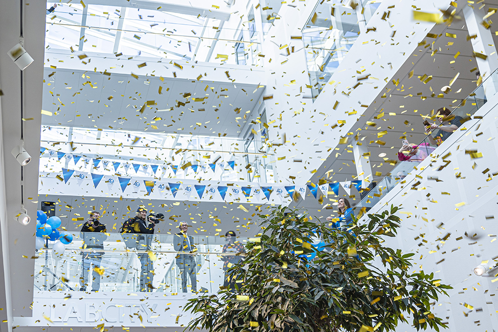 Golden confetti in the air, green plant and people in the background on a balcony. Photo.