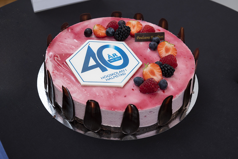 Tårta med en symbol uppe på, choklad på sidorna med svart bakgrund. Foto.