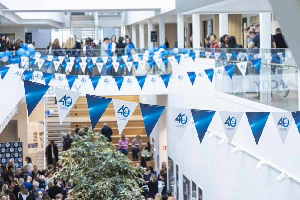 Vimplar hänger över en öppen yta med folk på olika våningar. Foto.