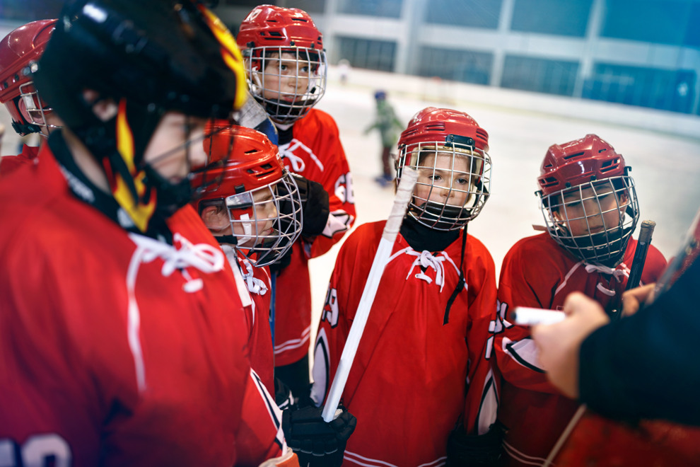 Några unga ishockeyspelare samlades runt sin tränare och gav instruktioner. Foto.