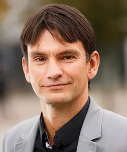 Man med grå kavaj och brunt hår som tittar in i kameran: Foto.