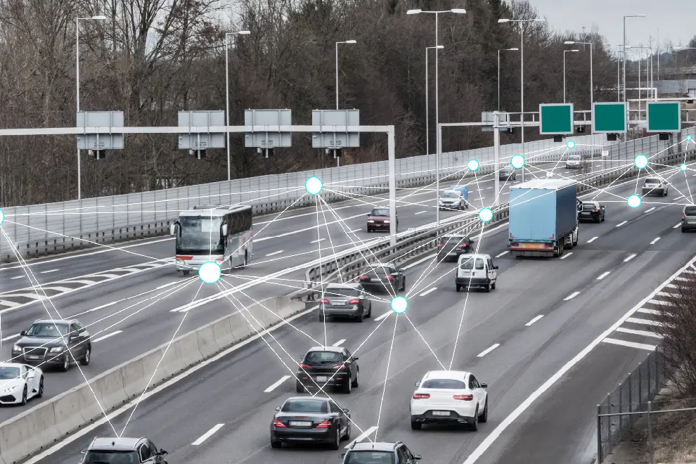 En motorväg med mycket trafik intill en skog. Digitala ljuspunkter syns över bilarna. Foto/illustration