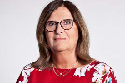 Person med röd tröja och glasögon som ler mot kameran