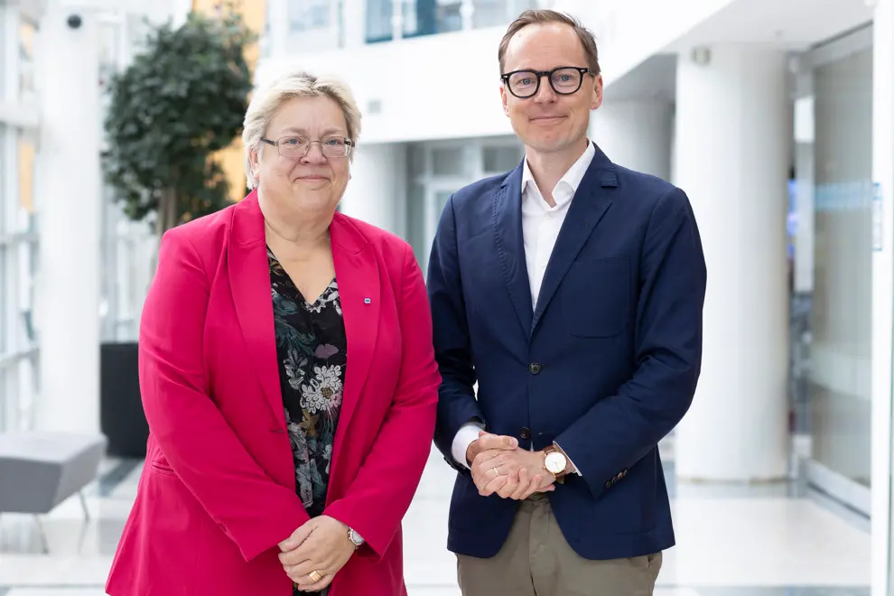 En man och en kvinna står bredvid varandra och och ler in i kameran. Foto