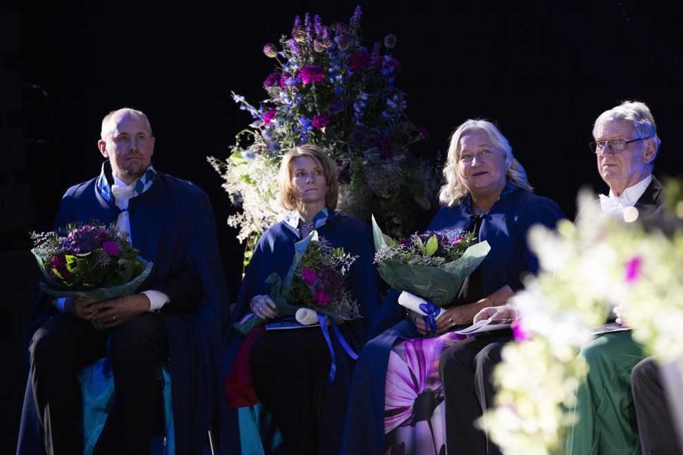 Fyra personer sitter på en scen. Fotografi.