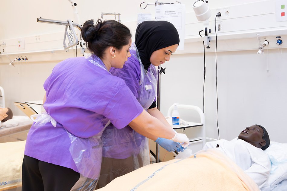 En leende kvinna håller en surfplatta och visar den för en man som står bredvid. Foto.