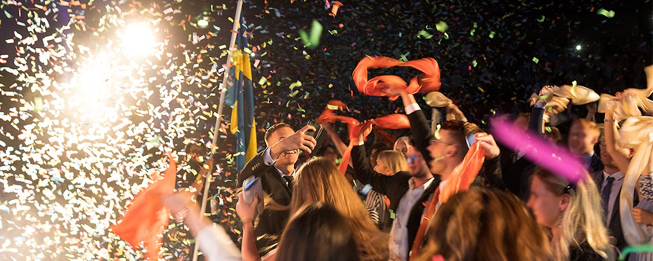 Happy people waving colored shawls in a confetti rain. Photo.