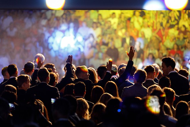 In the photo there is a crowd in an arena. Spotlights in different colours are aimed at the crowd. Photo.