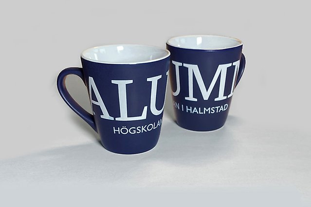 Two blue coffee mugs with white text are standing on a white surface. Photo.