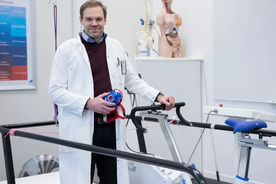 Person i labbmiljö brevid en motionscykel.