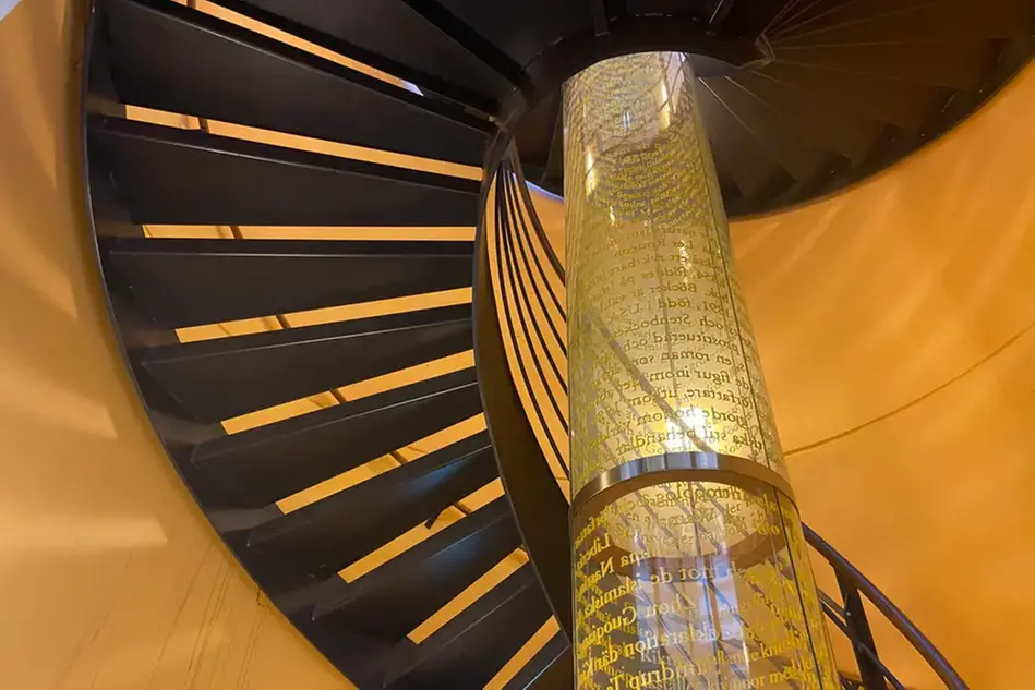 En mörk spiraltrappa slingrar sig runt ett konstverk.