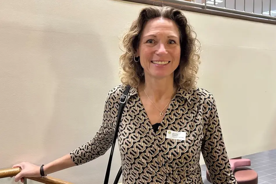 Person i inomhusmiljö ler och tittar in i kameran. 