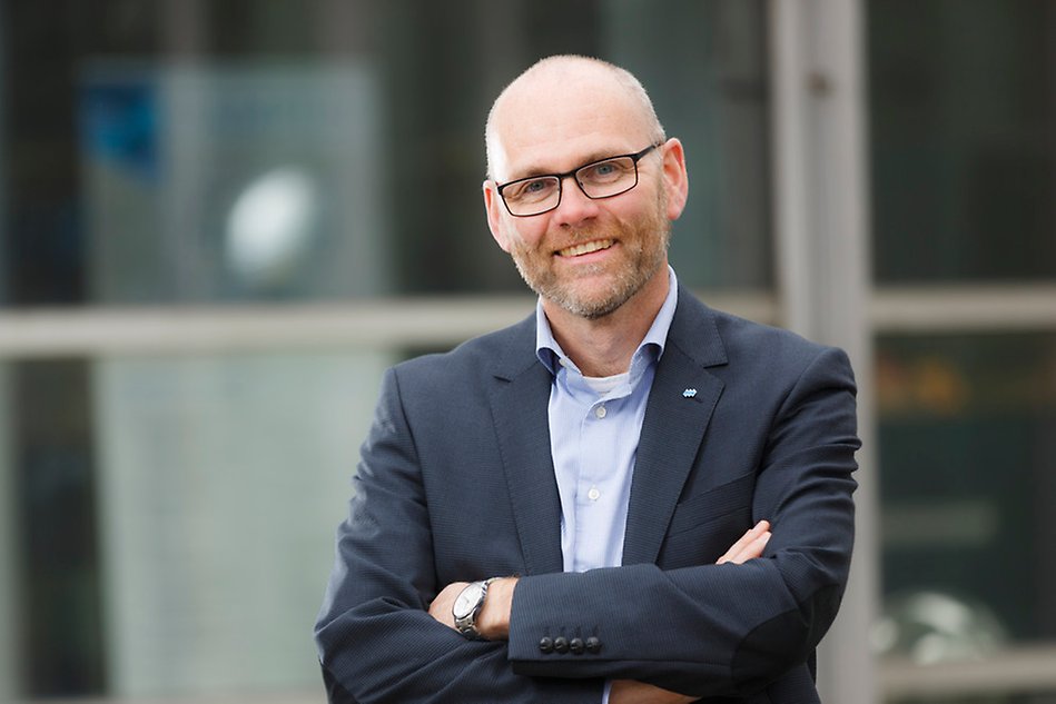 Man, dark blue jacket, smiling, glases.