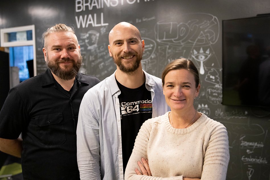 Two men and one woman smiling at the camera. Photo.