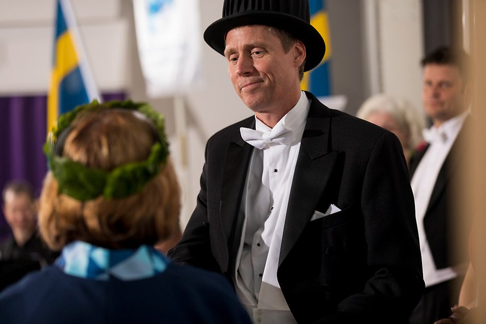 Man iklädd doktorshatt tar emot utmärkelse. 