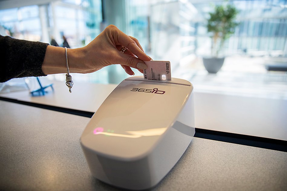 A hand scans a driver's license in an ID scanner. Photo. 