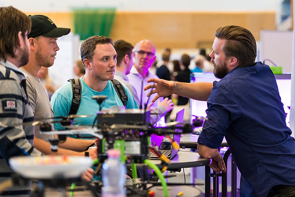 People gathered around a drone sitting on a table. Photo.