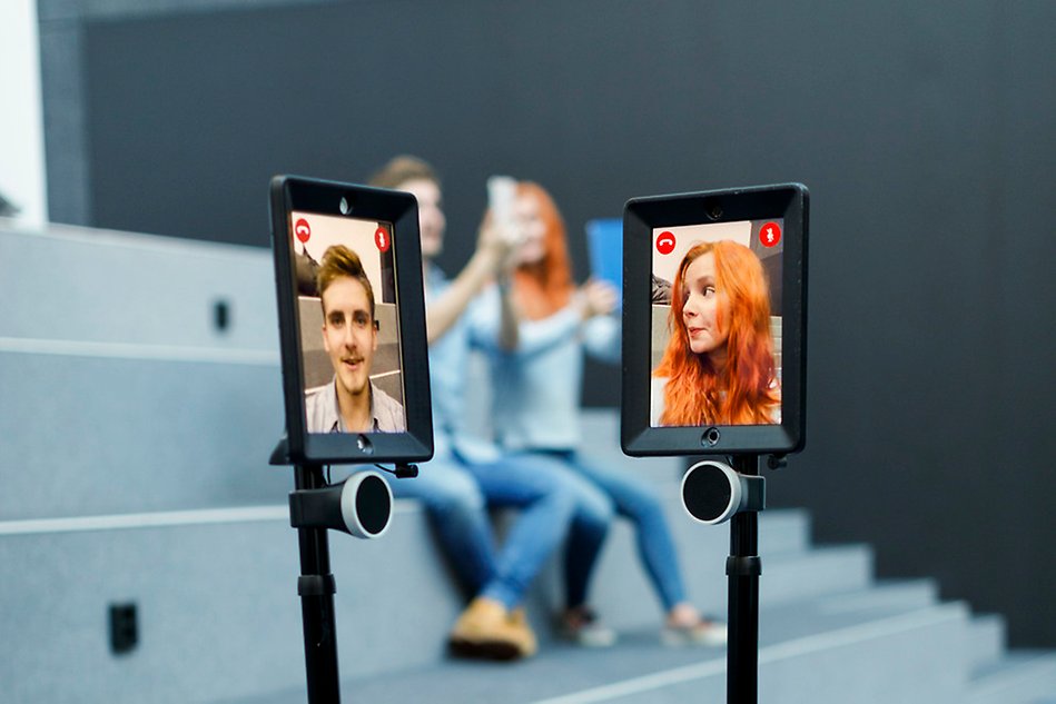 Two digital tablets are facing each other, one man and one woman are on the screens. Photo. 