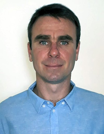 A portrait of a man wearing a blue shirt.