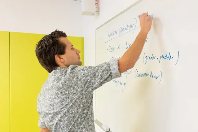 En man skriver på en whiteboard. Foto.
