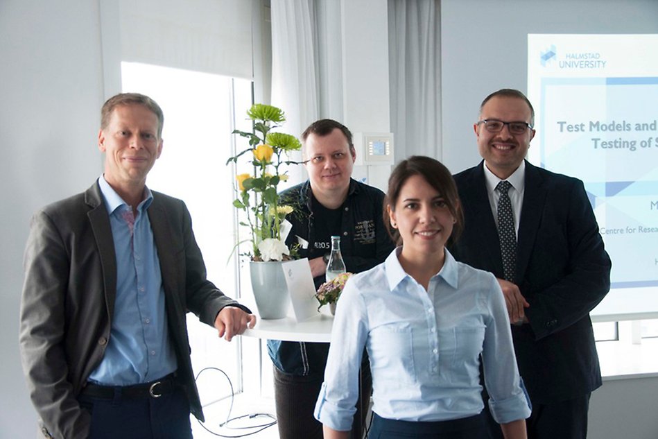 Three men and a woman standing in a conference room.