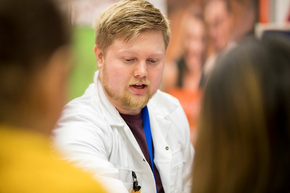 Man tittar ned och visar något utanför bilden för två andra personer