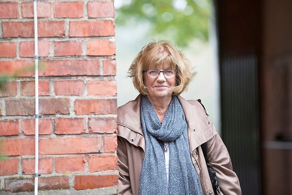 Woman leaning against a red brick wall