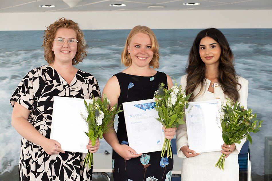 Tre kvinnor med diplom och blommor i händerna