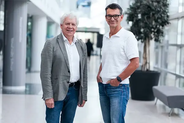 Två personer ler och tittar in i kameran. Foto